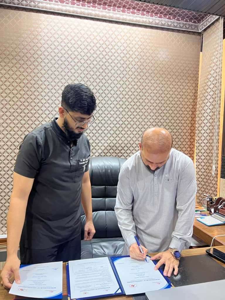 Close-up of Mr. Adnan Munir signing the MOU document while Dr. Sajeel Adrees oversees